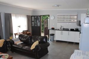 a living room with a leather couch and a kitchen at Giraffe's Rest, Self Catering Studio Apartment in White River