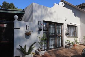 a white house with potted plants on the side of it at Giraffe's Rest, Self Catering Studio Apartment in White River