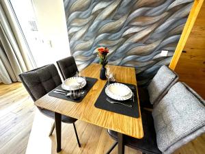 埃本塞Appartement Bergmann的餐桌、两把椅子和一张带玻璃杯的木桌