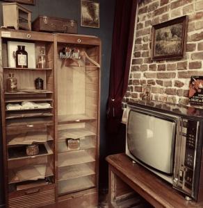 a living room with a tv and a brick wall at Escap'Home - Appartement insolite - Enquête dans l'hébergement et option séance d'escape game le jour du départ in Friville-Escarbotin