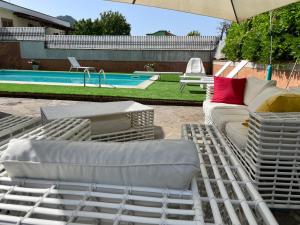 eine Gruppe weißer Liegestühle und ein Sonnenschirm neben einem Pool in der Unterkunft Villa Morena in Cava deʼ Tirreni