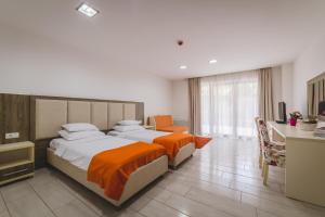 a hotel room with two beds and a desk at Hotel & Apartments HEC Residence in Sveti Stefan