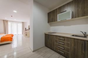 a kitchen with wooden cabinets and a bed in a room at Hotel & Apartments HEC Residence in Sveti Stefan
