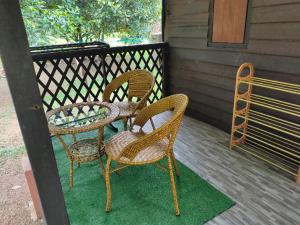 three wicker chairs and a table on a porch at NUR RAMADHAN CAMPSITE in Tanjung Malim