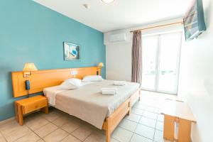 een slaapkamer met een bed met een blauwe muur bij Kos City Apartments in Kos-stad