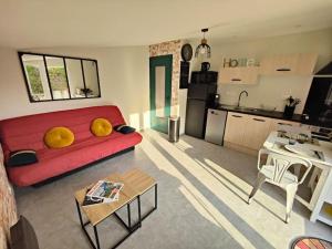 un soggiorno con divano rosso e una cucina di Appartement moderne en rez de jardin - La Cascade 