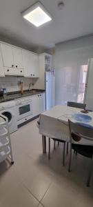 a white kitchen with a table and a refrigerator at Apartamento Larisa in Nájera