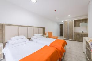 two beds in a bedroom with an orange blanket at Hotel & Apartments HEC Residence in Sveti Stefan