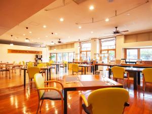 a dining room with tables and yellow chairs at Hotel BELLMARE ホテルベルマーレ in Maizuru