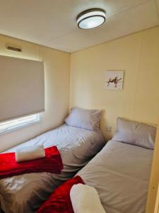 two beds in a small room with a window at New Beaches: Butternut in Dymchurch