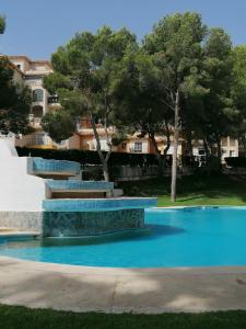 basen z błękitną wodą oraz drzewami i budynkami w obiekcie Campoamor Seaview w mieście Campoamor