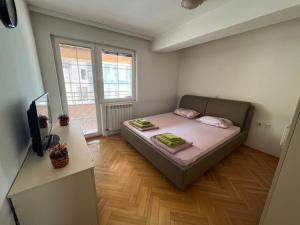 ein kleines Schlafzimmer mit einem Bett und einem TV in der Unterkunft Centar Luxory Apartmans in Skopje
