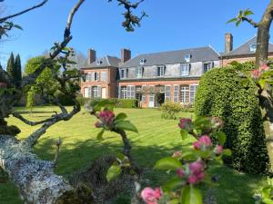 une grande maison avec une cour verdoyante ornée de fleurs roses dans l'établissement Château d'Aigneville, à Aigneville