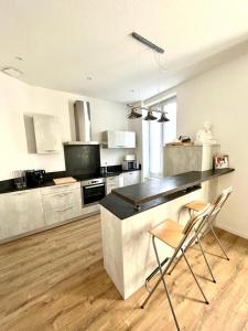 a kitchen with a counter and two chairs in it at Le Gamay - Charmant T2 avec parking et Terrasse in Châtel-Guyon