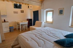 a bedroom with a large bed and a table at Nonna Clara, monolocale in Pieve di Cadore