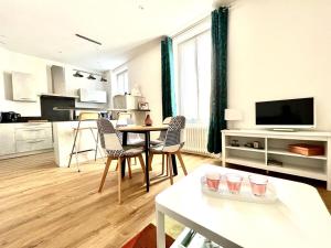a living room with a table and chairs and a kitchen at Le Gamay - Charmant T2 avec parking et Terrasse in Châtel-Guyon