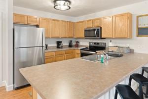 a kitchen with a stainless steel refrigerator and wooden cabinets at First Tracks 3301 Condo in Steamboat Springs