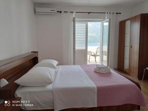 a white bedroom with two beds and a balcony at Apartments Panorama in Korčula