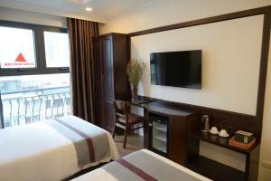 a hotel room with a bed and a desk with a television at Mercy Hotel in Hanoi