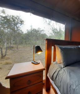 a bedroom with a bed and a lamp on a table at Wild Nature Lodge, Mareeba Wetlands in Biboohra