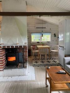 ein Wohnzimmer mit einem gemauerten Kamin und einem Tisch in der Unterkunft Summer Cottage with boat in Hudiksvall