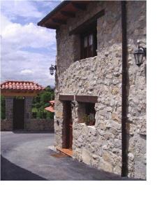 un edificio de piedra con puerta y porche en Casa El Carrelu, en Póo