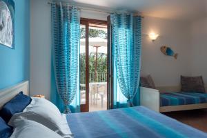 a bedroom with blue curtains and a bed and a balcony at Residence Costa d’Otranto in Otranto