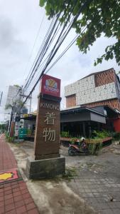 a sign in front of a building next to a street at Kimono Spa Hotel in Kuta