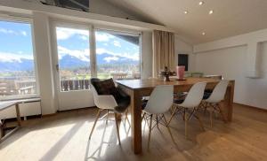 una sala da pranzo con tavolo, sedie e una grande finestra di Luxury Alpine Retreat with Wellness Area a Flims