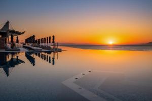 een zonsondergang boven een waterlichaam met een pier bij Michelangelo Resort & Spa in Ágios Fokás