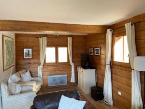 een woonkamer met houten wanden, een bank en ramen bij Chalet Cannon- Mountain Getaway in Les Contamines-Montjoie