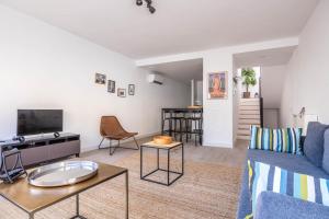 a living room with a couch and a tv at Slow Sevilla suite - two-bedroom apartment with private pool in Seville