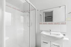 Un baño blanco con lavabo y ducha. en Sunset Retreat with Water Views, en Lakes Entrance