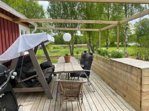 een houten terras met een tafel en stoelen onder een pergola bij Summer Cottage with boat in Hudiksvall