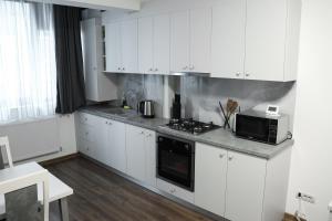 a white kitchen with a stove and a microwave at Nordic Residence 1 in Suceava