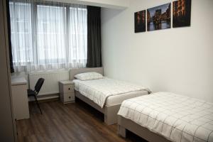 a bedroom with two beds and a desk and window at Nordic Residence 1 in Suceava
