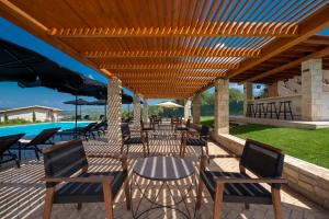 un patio con mesas y sillas bajo una pérgola de madera en Mint Retreat Suites en Kalandra