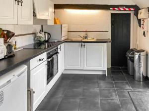 a kitchen with white cabinets and gray tile floors at The Hive - Uk44558 in Plaistow