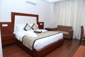 1 dormitorio con 1 cama grande con silla y silla en The Grand Kartikeye Hotel & Banquet Destination en Pālampur