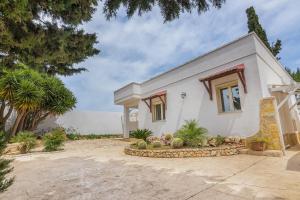 ein weißes Haus mit Bäumen und Pflanzen davor in der Unterkunft Residence Dolce Vita in Torre Lapillo