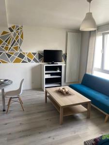 a living room with a blue couch and a table at La Pause Pétillante in Sélestat