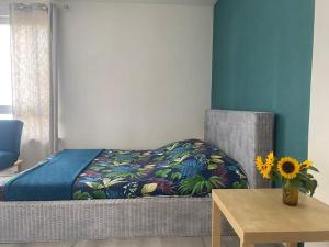 1 dormitorio con cama, mesa y jarrón con girasol en La Pause Pétillante en Sélestat