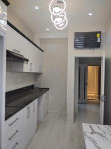 a large kitchen with white cabinets and a chandelier at Элит 5 in Khujand