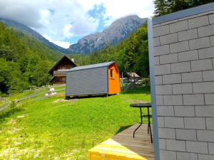 un pequeño cobertizo en un campo con montañas en el fondo en Camping & Glamping Grintovec, en Preddvor