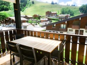 a wooden table and chairs on a balcony at Appt les Granges - Vue montagne et village, Centre la Clusaz - AravisTour in La Clusaz