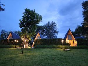a night view of a house with lights in the grass at Phusira ภูศิรา กาญจนบุรี 