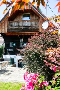 Casa de madera con balcón y flores rosas en Winzerhaus Rose 