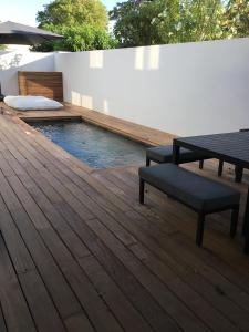 una terraza de madera con un banco y una piscina en Villa avec piscine bord de mer CARNON en Carnon-Plage