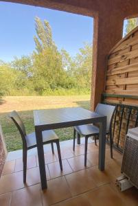 een tafel en stoelen op een patio met een raam bij Joli Appartement 27m2 Terre d'Ocre en village vacances en Camargue in Arles
