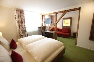 a bedroom with a white bed and a red couch at Hotel Schmidt am Markt in Meppen